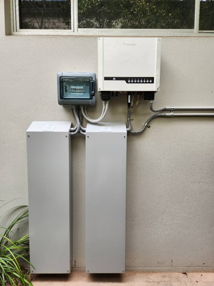 A 20 kWh installation of two slim cabinets against an exterior wall with an inverter and monitoring unit