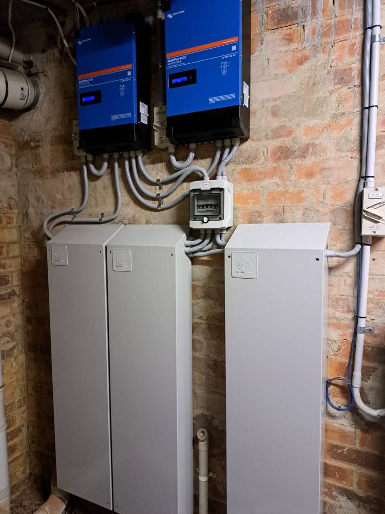 A 30 kWh installation of three battery cabinets with two inverters on a brick wall