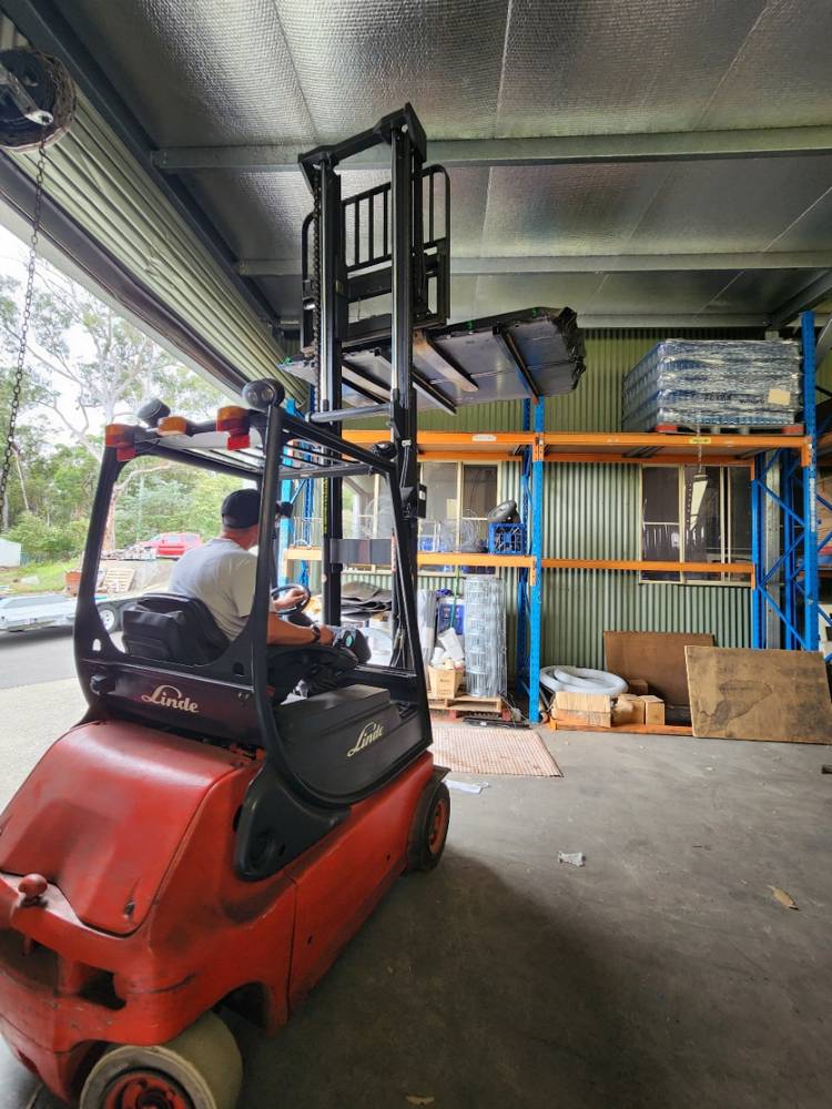 A battery being moved by forklift into an industrial building for installation