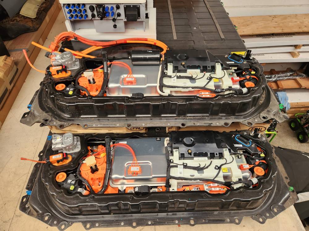 Two traction packs set up on a bench with orange high-voltage cabling for cycle testing